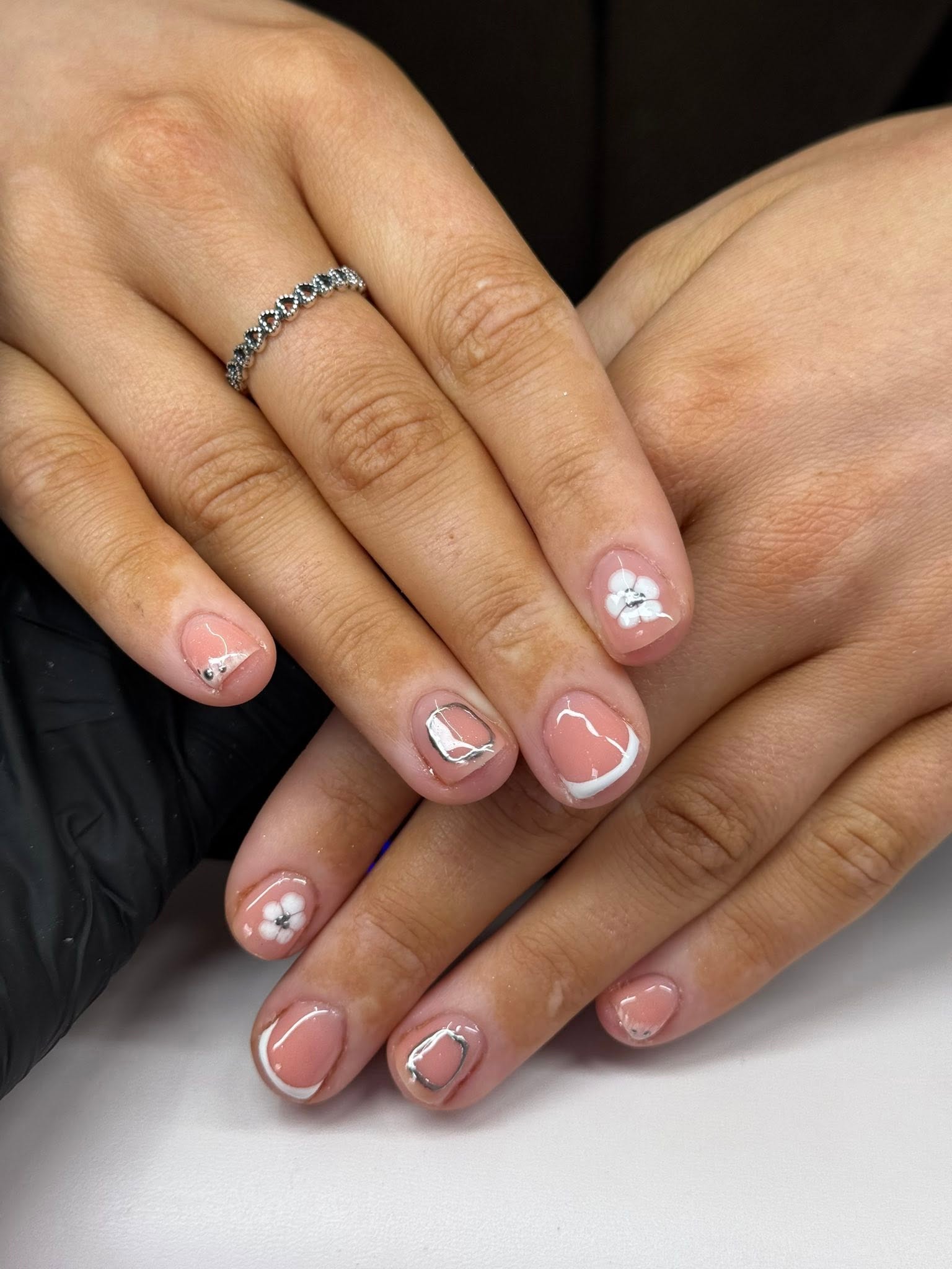Nail art with delicate white flower and chrome French tip detail